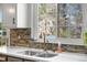 Bright kitchen sink with stainless steel faucet, stone backsplash, and ample natural light from the window at 15865 E Kepner Dr, Aurora, CO 80017