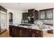 Kitchen island featuring dark cabinets, granite counters, gas cooktop, and stainless steel appliances at 5301 S Birch Ct, Greenwood Village, CO 80121
