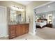 Bathroom with a large mirror over a granite topped vanity and a bedroom can be seen through the doorway at 12147 S Shady Pine Ct, Parker, CO 80134