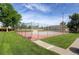 Fenced tennis court surrounded by green grass and mature trees, a wonderful amenity for residents at 10251 W 44Th Ave # 7-106, Wheat Ridge, CO 80033