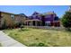 Spacious backyard featuring a lush green lawn, picket fence, and a two-story purple home at 8335 E 22Nd Ave, Denver, CO 80238