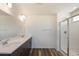 This bathroom boasts double sinks, modern fixtures, a glass-enclosed shower, and stylish wood-look flooring for a sleek look at 2177 Garden Ave, Brighton, CO 80601