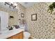 Small powder room features a vintage floral wallpaper with sink, toilet, and mirror at 19447 E Bellisario Creek Dr, Parker, CO 80134