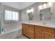Bright bathroom featuring double sinks, wood cabinets, tub, and modern fixtures at 3563 Watada Dr, Brighton, CO 80601
