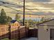 Backyard view showcasing the wooden fence, detached garage, and city skyline at sunset at 3401 N Steele St, Denver, CO 80205