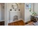 Bright living room with a decorative fireplace mantel, round mirror, and hardwood floors at 3401 N Steele St, Denver, CO 80205