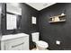 Powder room features sleek black walls, modern fixtures, and a floating shelf with stylish decor at 6707 S Elizabeth St, Centennial, CO 80122