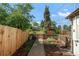 A fenced in backyard with wooden fence, garden, greenery, mulch, and a stone path at 5090 W 36Th Ave, Denver, CO 80212