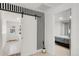 Hallway features a sliding barn door, striped accent wall, and light hardwood floors at 5090 W 36Th Ave, Denver, CO 80212