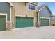 Attached two car garages with green doors and stone accents at 529 Gallegos Cir, Erie, CO 80516