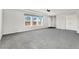 Large living room featuring gray carpet, three windows with views, and neutral paint at 449 Dunmire St, Frederick, CO 80530