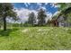Expansive backyard with lush green grass, mature trees, and a charming wooden deck on house at 25694 Stansbery St, Conifer, CO 80433