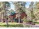 Charming log home has wood siding and a green metal roof nestled among trees and landscaping at 5030 Cedar Way, Elizabeth, CO 80107