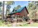 Charming log home with a green metal roof, deck, and inviting outdoor space surrounded by tall trees at 5030 Cedar Way, Elizabeth, CO 80107