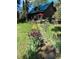 Two-story home with a green roof nestled in a wooded area, highlighted by a colorful flower garden at 5030 Cedar Way, Elizabeth, CO 80107