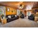 Comfortable living room boasts wood-paneled walls and a view into the open kitchen and dining area at 5030 Cedar Way, Elizabeth, CO 80107