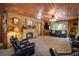 Cozy living room featuring a stone fireplace, wood-paneled walls, plush seating and a view of the trees at 5030 Cedar Way, Elizabeth, CO 80107