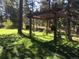 Shaded pergola on a grassy lot with mature trees offering a place to relax and enjoy the surroundings at 5030 Cedar Way, Elizabeth, CO 80107