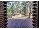 Inviting covered patio provides a serene view into the wooded property at 5030 Cedar Way, Elizabeth, CO 80107