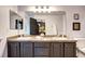 Well-lit bathroom with a dual-sink vanity, light brown countertop, and view to bedroom at 800 Rockhurst Dr # D, Highlands Ranch, CO 80129