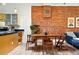 Dining area with wooden table and chairs next to exposed brick wall, opening to kitchen and living room at 361 Elati St, Denver, CO 80223