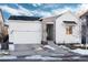 White two-story house with stone accents and a two-car garage, snowy landscape at 6437 Saddlesmith St, Castle Pines, CO 80108