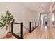 Modern hallway with light wood floors and a cable railing staircase at 6437 Saddlesmith St, Castle Pines, CO 80108