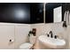 Stylish powder room with a pedestal sink and dark-painted walls at 6437 Saddlesmith St, Castle Pines, CO 80108