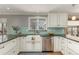 Farmhouse sink and stainless-steel appliances, complemented by white cabinets and granite countertops at 2365 S Holly Pl, Denver, CO 80222