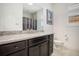 This bathroom offers dark cabinets with granite countertops, a framed mirror, and natural light at 6674 Fonder Villa Dr, Parker, CO 80134