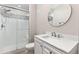 Modern bathroom featuring a walk-in shower with decorative tiles, a vanity with a sink, and a round mirror at 8035 S Kewaunee St, Aurora, CO 80016