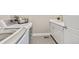 Bright laundry room with sleek white cabinets, modern washer, and gray tile flooring at 8035 S Kewaunee St, Aurora, CO 80016