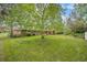 Lush green backyard with large tree, fenced area, and glimpse of home exterior at 8269 Zephyr St, Arvada, CO 80005