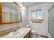 Well-lit bathroom featuring vanity sink, medicine cabinet, and a shower with sliding glass door at 8269 Zephyr St, Arvada, CO 80005