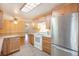 Well-lit kitchen featuring stainless steel refrigerator, light wood cabinets, and stone countertops at 8269 Zephyr St, Arvada, CO 80005