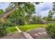 Grassy backyard featuring a fire pit, landscaping, and mature trees at 6748 S Gallup St, Littleton, CO 80120