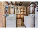 Basement laundry area with two washing machines, dryer, and unfinished wooden storage at 6748 S Gallup St, Littleton, CO 80120