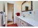 Vintage style bathroom with white tile, red tile floor, and unique framed mirror and towel rack at 6748 S Gallup St, Littleton, CO 80120