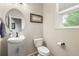 Cozy half bathroom with updated vanity, toilet, oval mirror, and a framed picture at 11725 Helena St, Commerce City, CO 80022