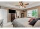 Cozy main bedroom with tray ceiling, fan, and large window, plus an ensuite bathroom at 11725 Helena St, Commerce City, CO 80022
