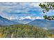 Scenic mountain landscape with snow-capped peaks and lush green forests in the foreground at 1007 Nob Hill Rd, Evergreen, CO 80439