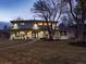 Charming two-story home with manicured lawn, mature tree, and welcoming entrance, beautifully lit at twilight at 6111 W Fremont Dr, Littleton, CO 80128