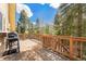 Spacious back deck with wood railing provides a beautiful view of the surrounding trees at 9185 Jill Dr, Conifer, CO 80433