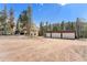 Inviting exterior of a two-story home with a three car garage and a large dirt lot surrounded by mature trees at 9185 Jill Dr, Conifer, CO 80433