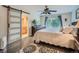 Comfortable bedroom with wood floors, ceiling fan, and sliding barn door to bathroom at 3265 W 11Th Avenue Ct, Broomfield, CO 80020