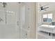 Bright bathroom featuring tiled shower with glass door, ceiling fan and views to a bedroom at 9002 Birch Run Dr, Parker, CO 80134
