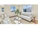 Well-lit living room featuring a plush white sofa, accent chairs, and large windows offering neighborhood views at 9002 Birch Run Dr, Parker, CO 80134