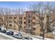 Multi-story brick apartment building featuring a glass-encased staircase, surrounded by mature trees and parked cars at 500 E 11Th Ave # 401, Denver, CO 80203