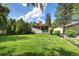 A spacious backyard with green grass, mature trees, and a view of the home's exterior at 6305 W 6Th Ave # C12, Lakewood, CO 80214