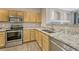 Kitchen with stainless steel appliances, granite countertops, and natural wood cabinetry at 12711 Colorado Blvd # 714G, Thornton, CO 80241